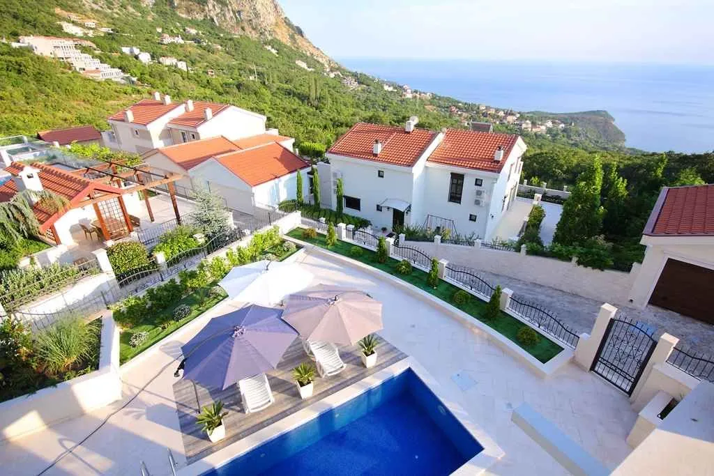 Pogled odozgo na kompleks vila sa bazenom i panoramskim pogledom na more.