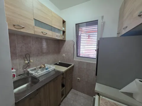 Small kitchen with wooden cabinets and a sink by the window. - image 11