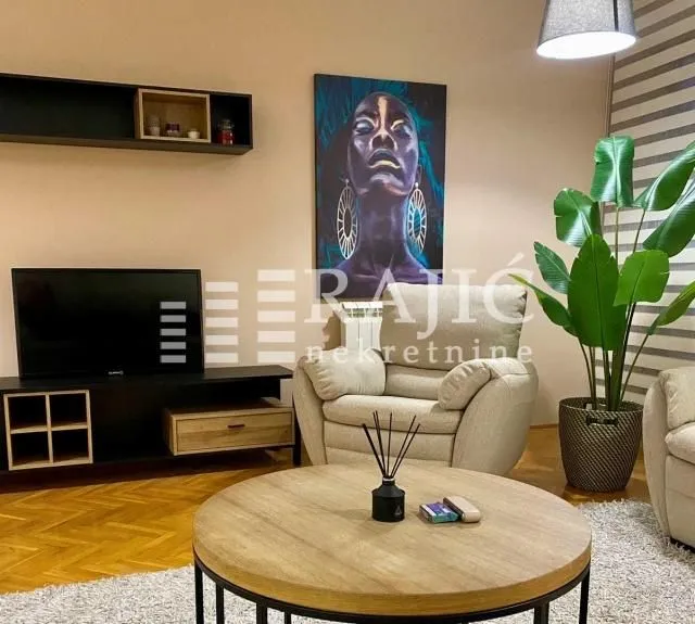 Furnished living room with a sofa set, TV, and decorative plants.