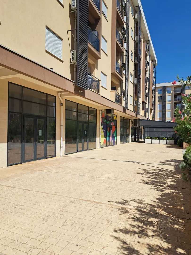 Exterior of a residential and commercial building with a paved plateau on the ground floor.