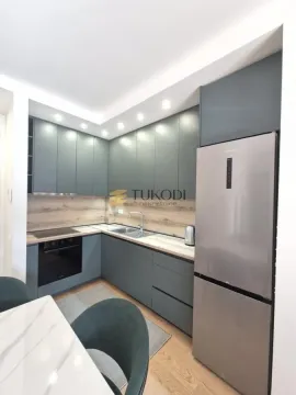 Modern corner kitchen in dark green tones with wooden elements and built-in appliances. - image 8
