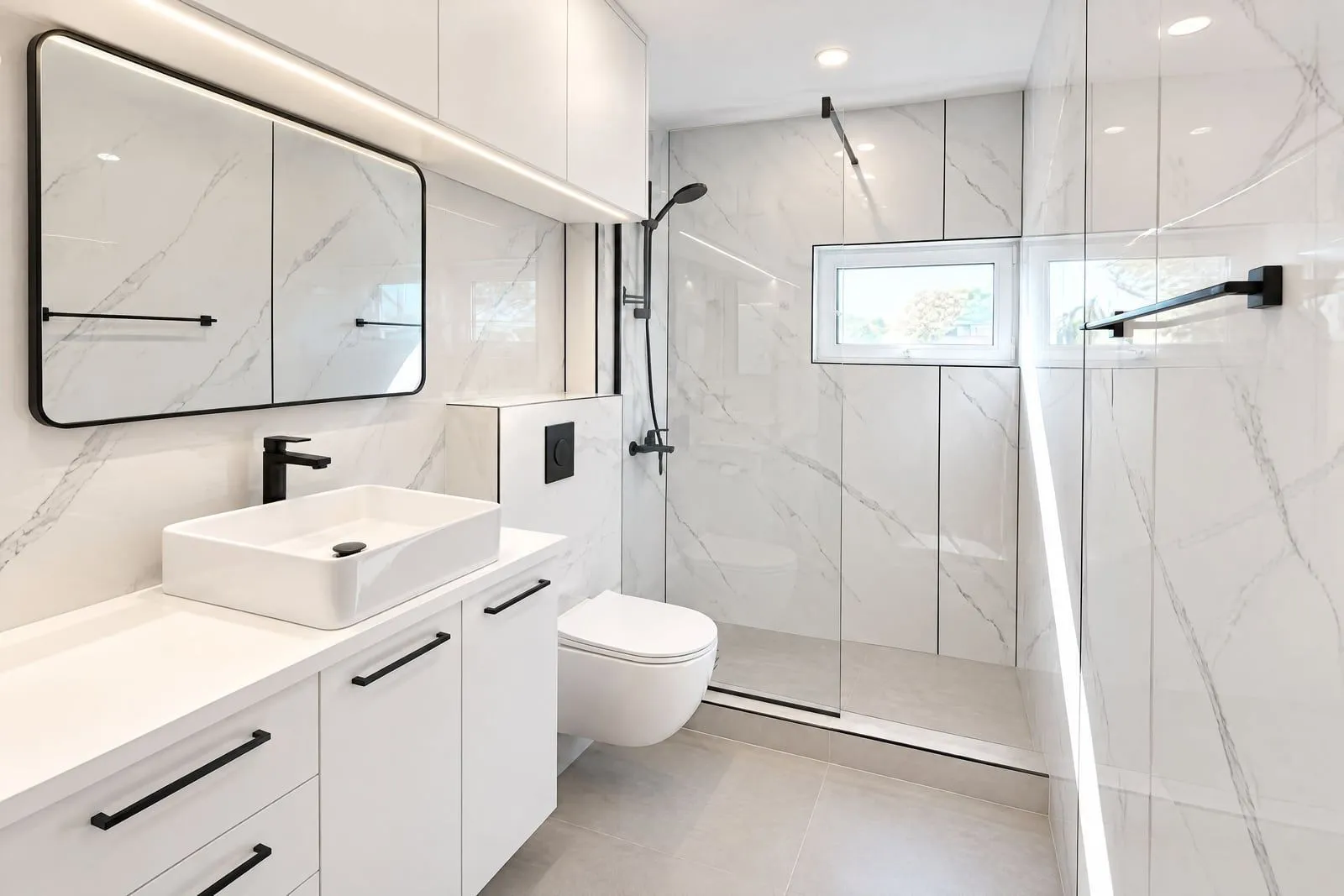 Modern and bright bathroom with white marble tiles and a walk-in shower.