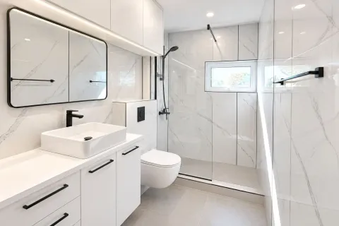 Modern and bright bathroom with white marble tiles and a walk-in shower. - image 11