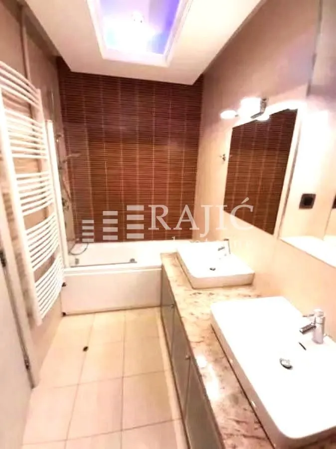 Modern bathroom with two sinks, a bathtub, and built-in lighting.