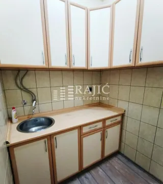 Small kitchen with a sink and wooden cabinets. - image 8
