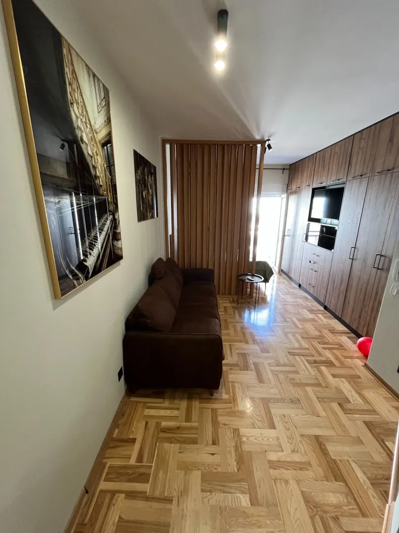 Dnevna soba sa braon trosjedom, drvenim namještajem i umjetničkim slikama na zidu.