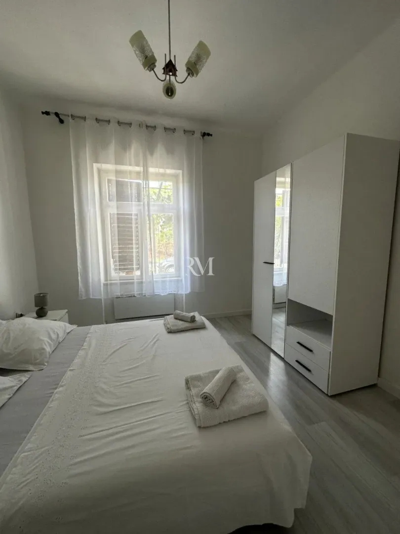 Bright bedroom with a double bed and a white wardrobe.