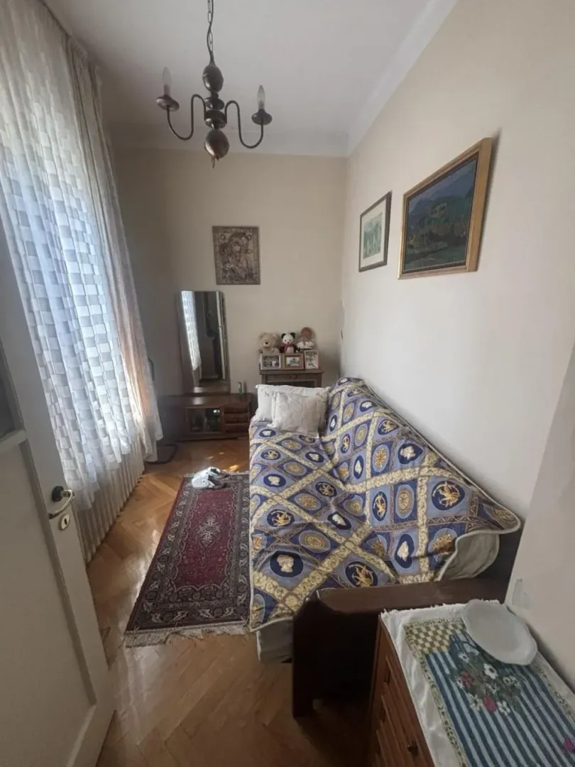 Small living room with a sofa, rug, and window with curtains.