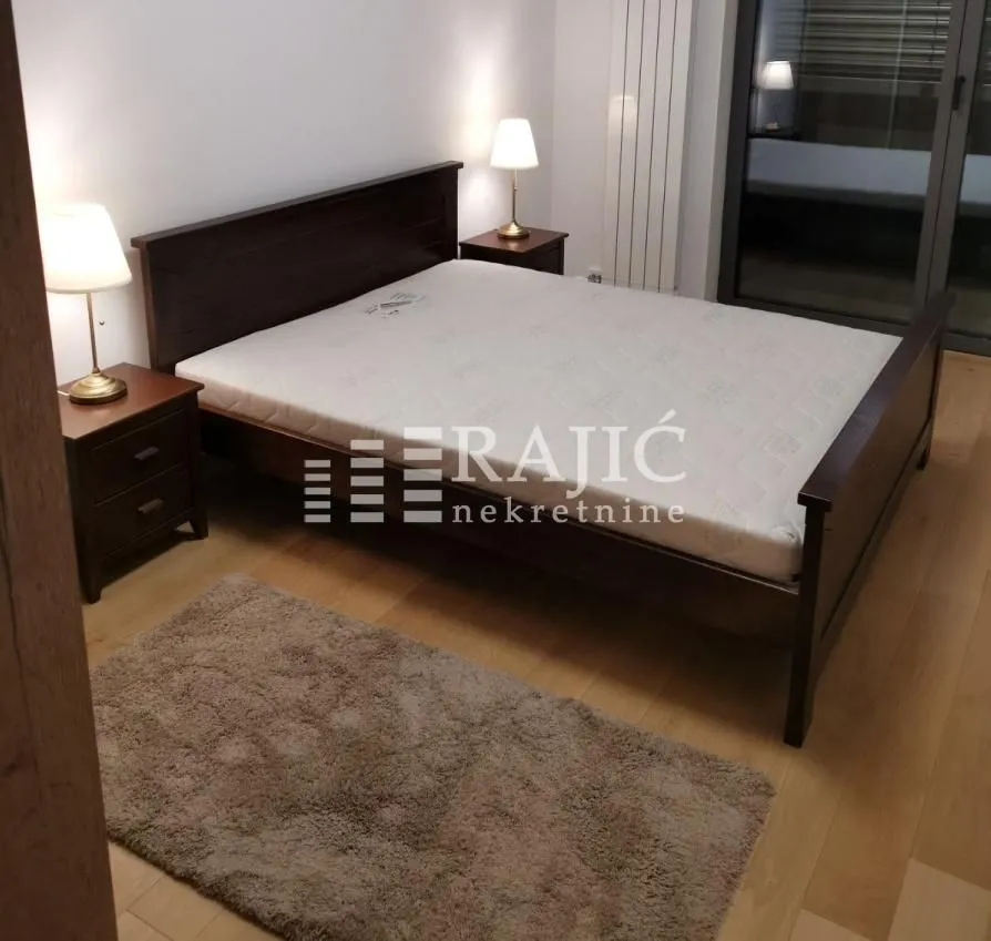 Furnished bedroom with a double bed, nightstands, and lamps.