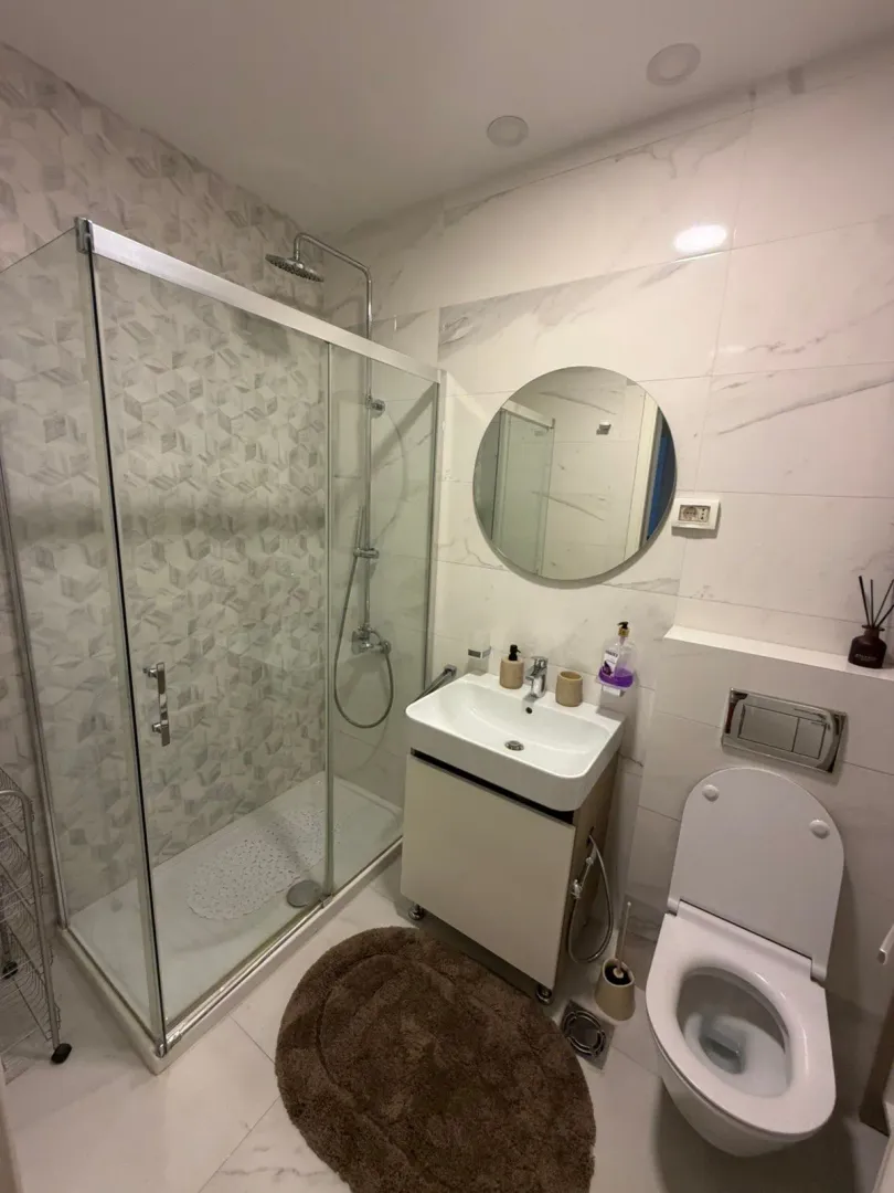 Modern bathroom with a shower cabin, washbasin, and toilet.