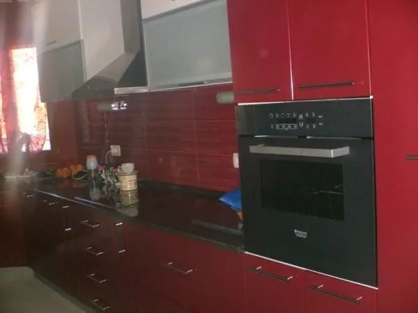 A modern red kitchen with a built-in oven.