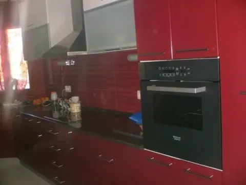 A modern red kitchen with a built-in oven. - image 7