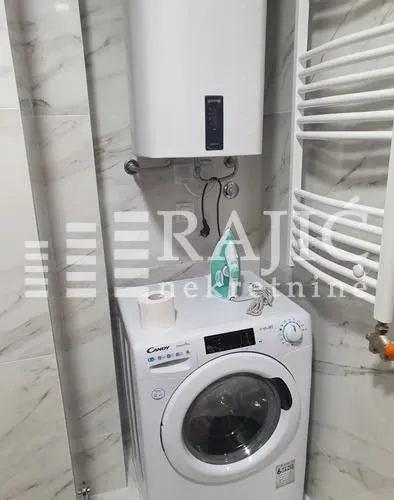 Part of the bathroom with a washing machine, boiler, and radiator.