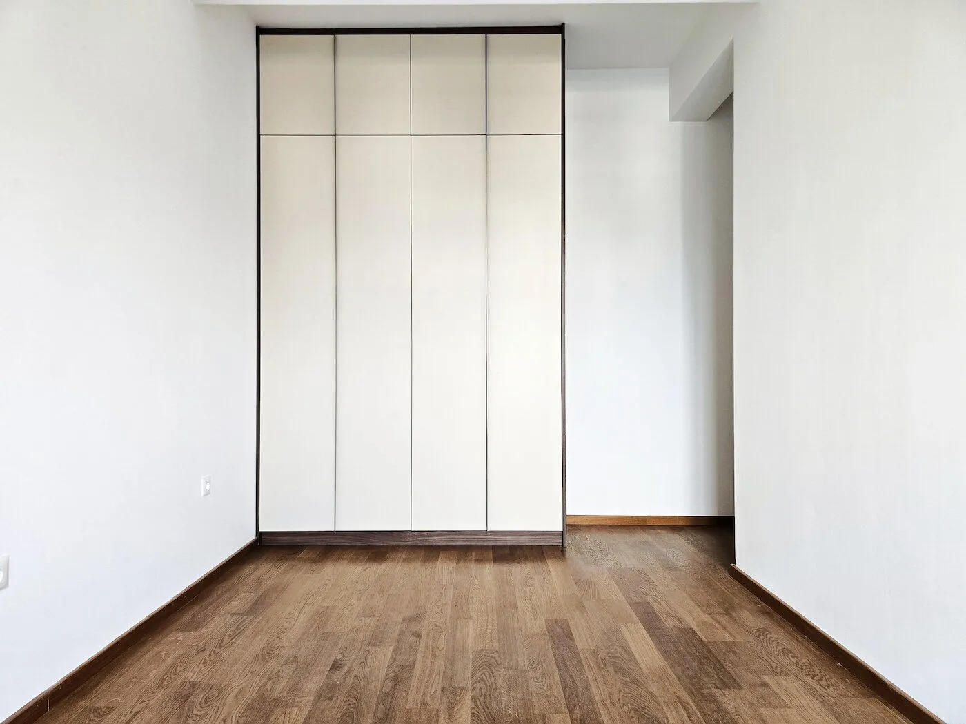 Empty room with a built-in wardrobe and hardwood flooring.