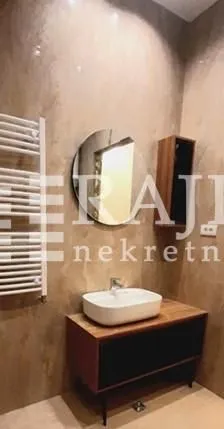 Moderno kupatilo sa umivaonikom, ogledalom i radijatorom.
