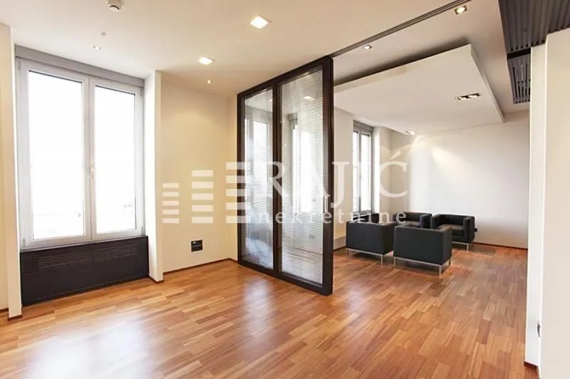 Spacious bright living room with parquet flooring and a glass partition wall.
