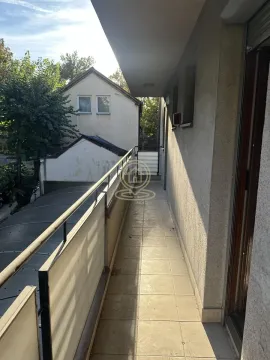 Long tiled balcony with a metal railing and a view of surrounding buildings and greenery. - image 14