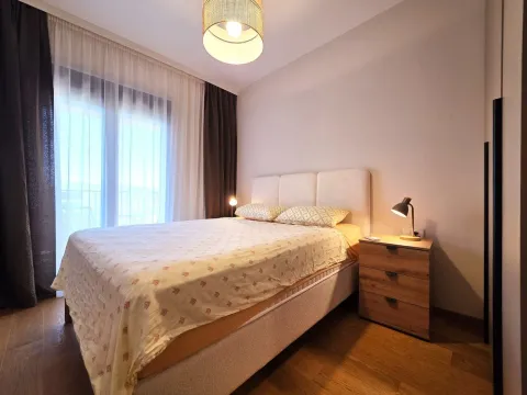 Uređena spavaća soba sa bračnim krevetom, noćnim stočićem i prozorom sa zavjesama. - image 8