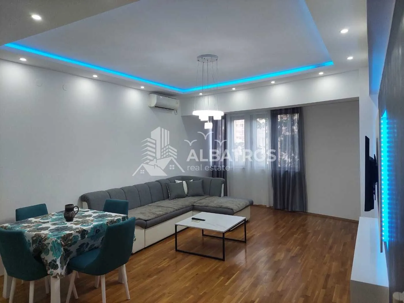 Living room with a sofa set, dining table, and dropped ceiling with lighting.