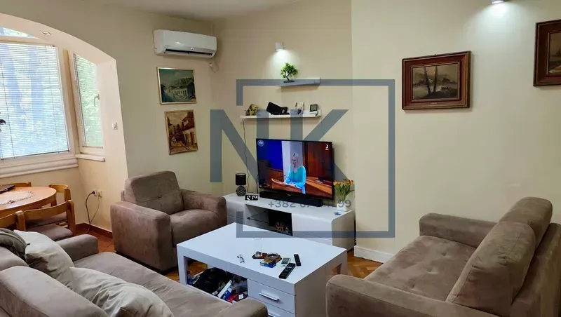 Dnevna soba sa garniturom, stočićem i televizorom.