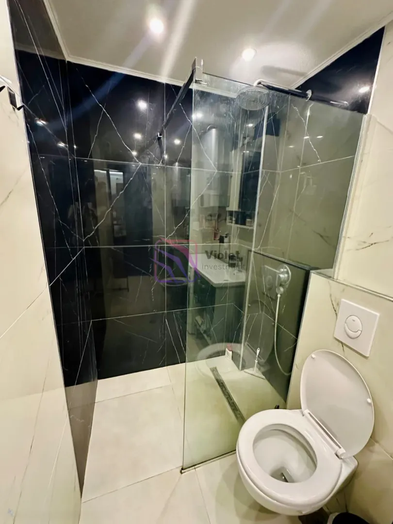 Moderno opremljeno kupatilo sa tuš kabinom i sanitarijama.