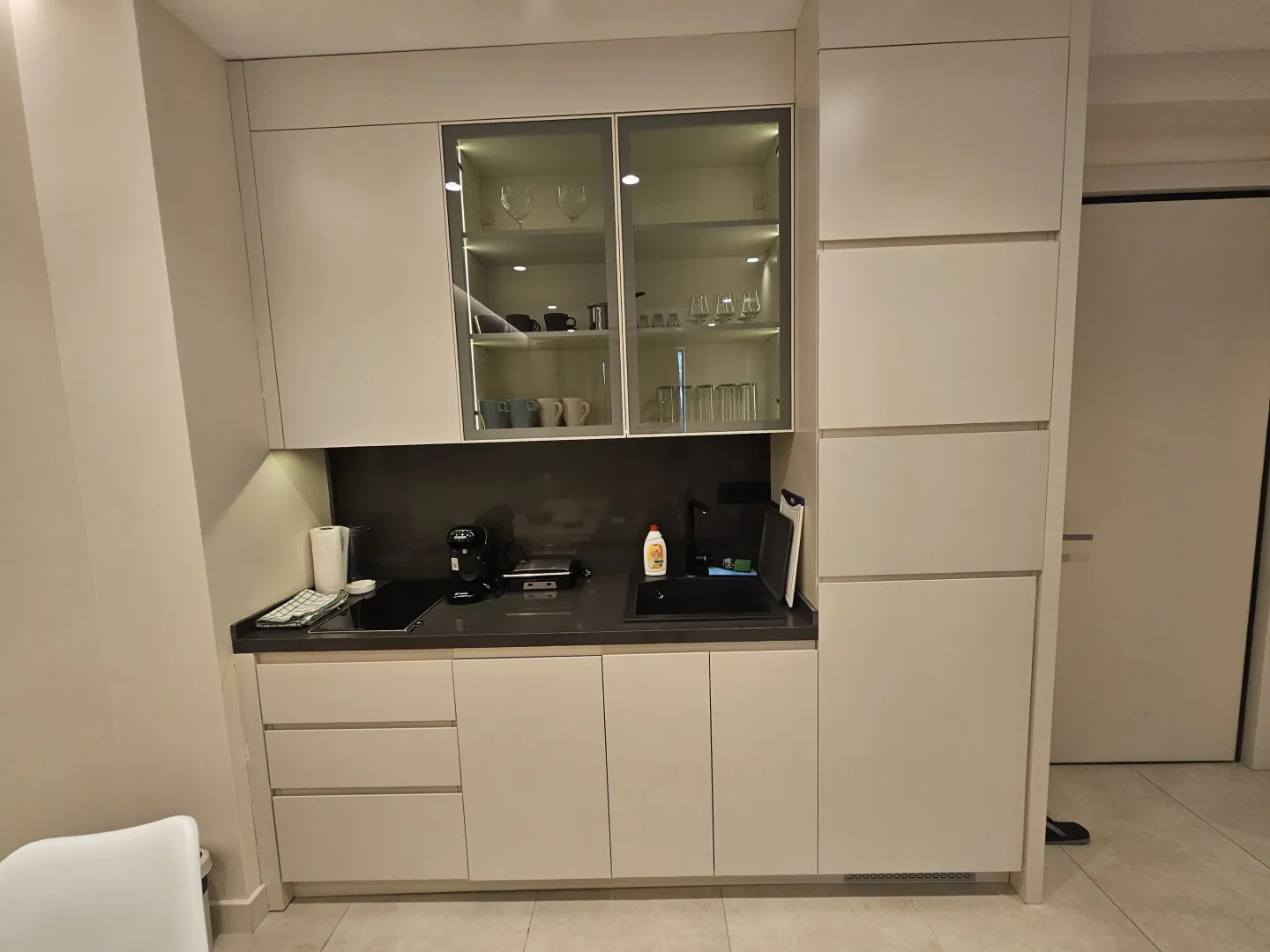 Modern kitchen with built-in cabinetry and illuminated glass display cabinets.