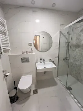Moderno kupatilo sa tuš kabinom, umivaonikom i okruglim ogledalom. - image 7