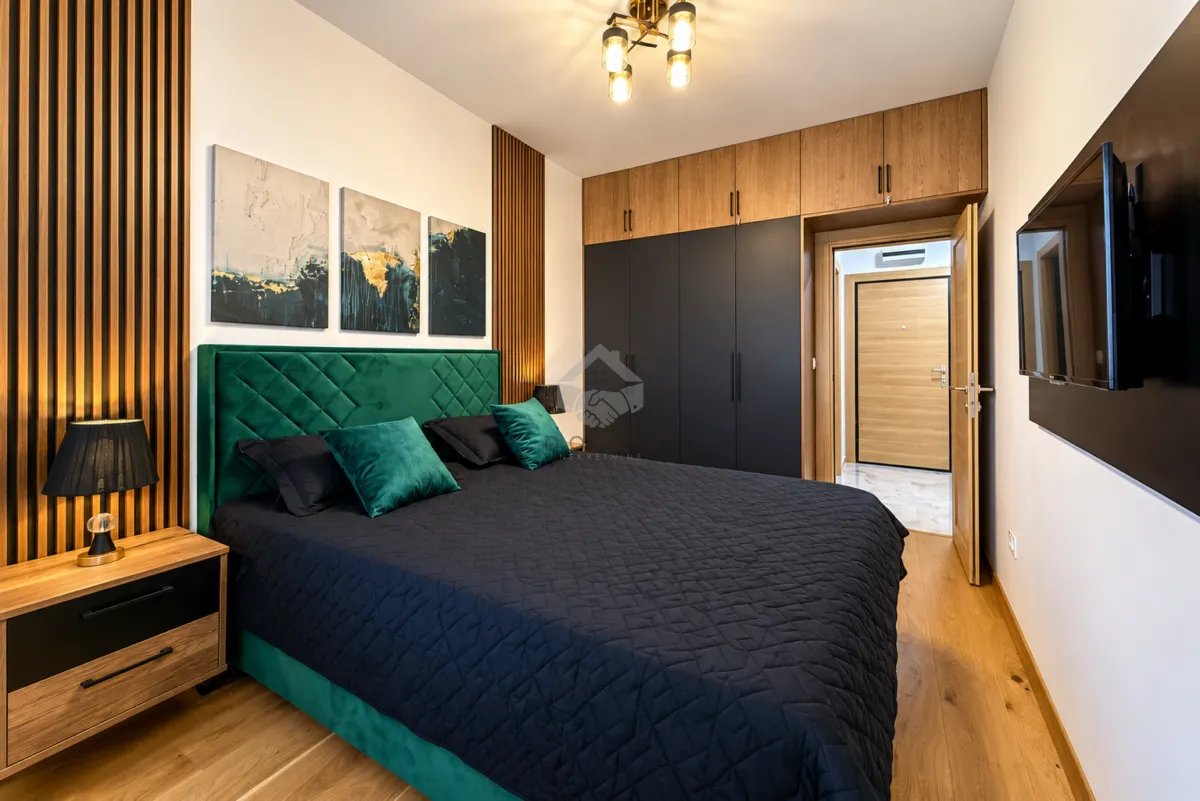Modern bedroom with a double bed, built-in wardrobe, and a TV.