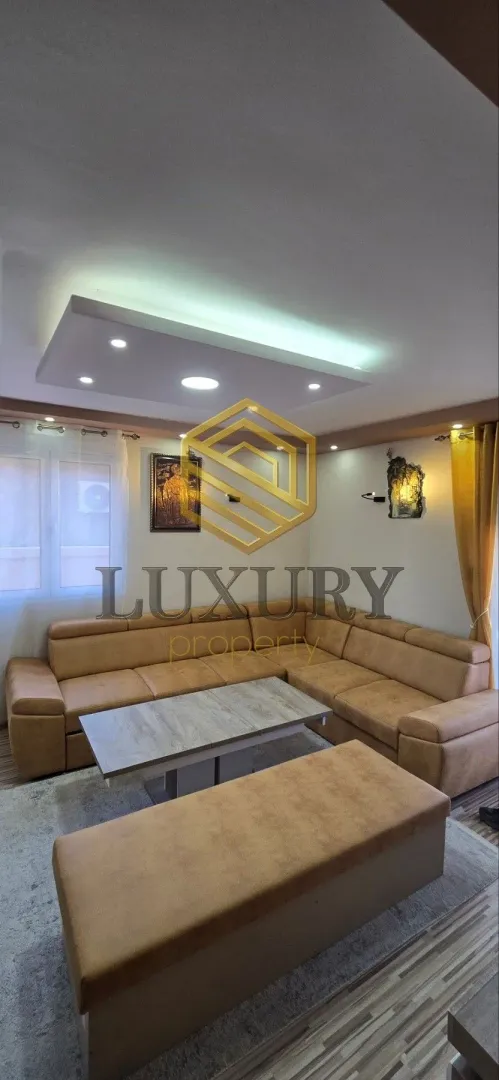Living room with a sectional sofa and modern ceiling lighting.