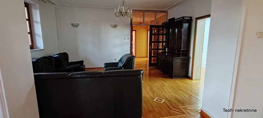Spacious living room with seating furniture and wooden cabinets.