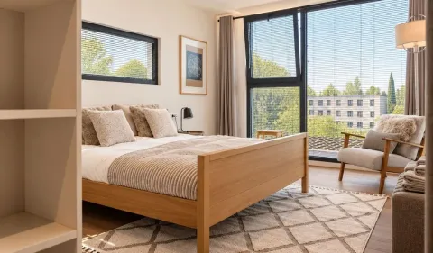 Spacious bedroom with a double bed, armchair and large windows. - image 12