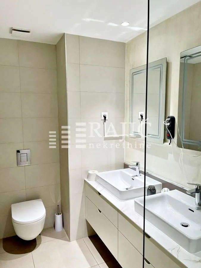 Modern bathroom with two sinks, toilet, and mirrors.