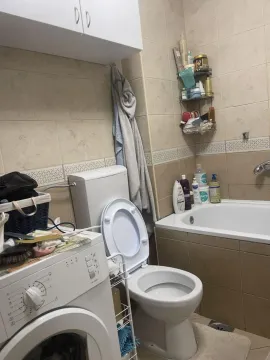 Smaller bathroom with a bathtub, toilet, and washing machine. - image 14