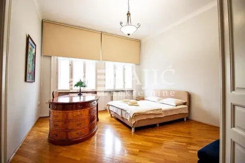Spacious bedroom with a double bed, wooden flooring, and a large vintage desk. - image 11