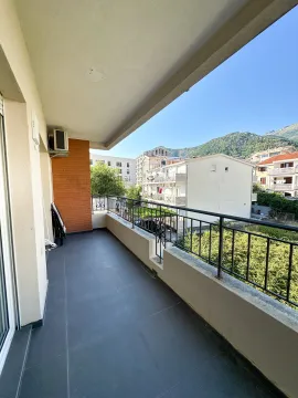 Spacious balcony with a view of surrounding buildings and hills. - image 8