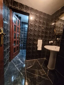 Bathroom tiled in dark tiles with a washbasin and a door. - image 18
