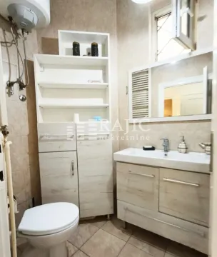 Smaller bathroom with a sink, toilet, cabinet, and water heater. - image 10