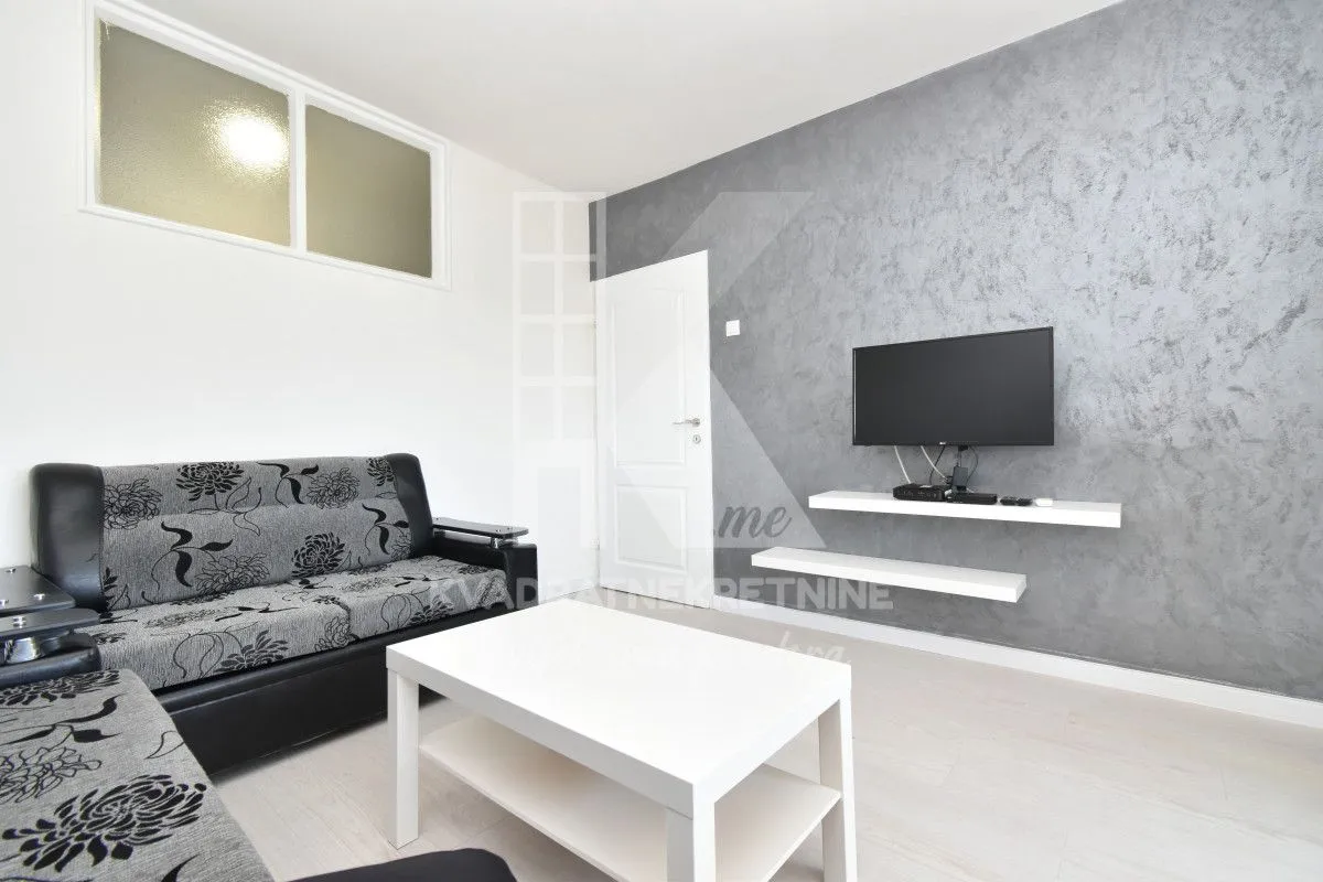 Living room with a sofa, coffee table, and a wall-mounted TV.