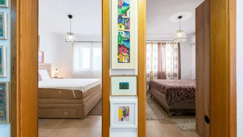 Pogled iz hodnika na dvije opremljene spavaće sobe sa krevetima. - image 9