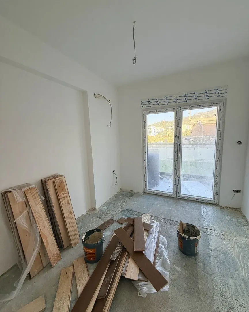 Empty room during renovation with hardwood flooring and installation materials.