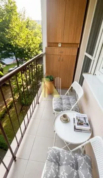 Manji namešten balkon sa stolom, stolicasima i drvenim ormarićem. - image 10