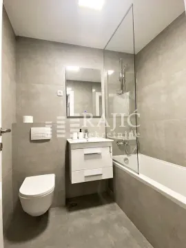 Modern bathroom equipped with a bathtub, washbasin, and toilet in gray tones. - image 12