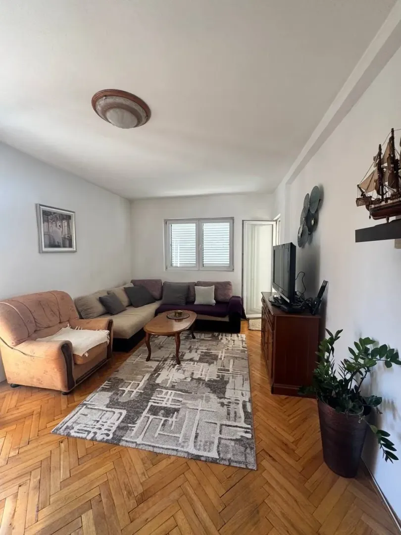 Living room with a sofa set, wooden floor, and a television.