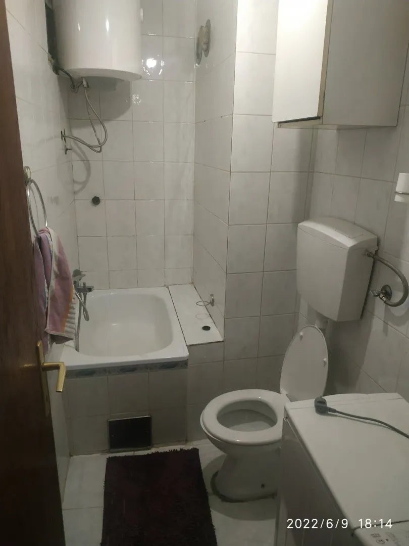 Jednostavno kupatilo sa malom kadom, toaletom i bojlerom.