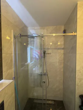 Bathroom with a shower cabin enclosed by a glass screen and ceramic tiles. - image 11