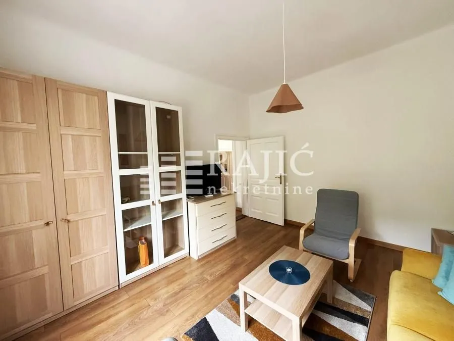 Living room with sofa, furniture units, and wooden wardrobes.