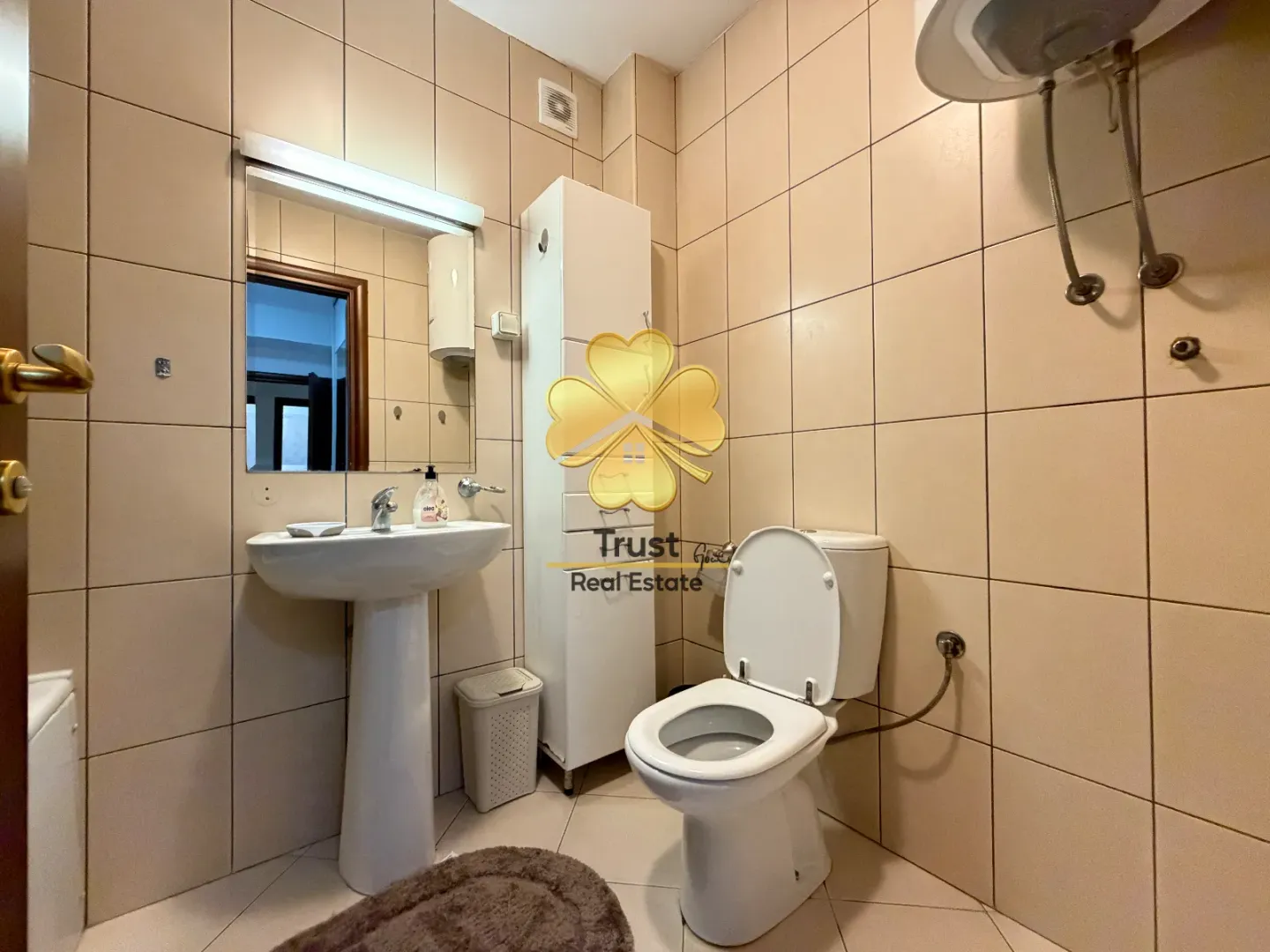 Manje kupatilo sa umivaonikom, WC šoljom i pločicama.
