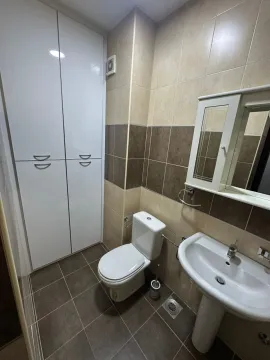 A practical bathroom with a toilet, sink, and built-in cabinet. - image 2