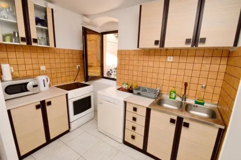 A functional kitchen featuring light-wood cabinets and beige tiled walls. - image 18