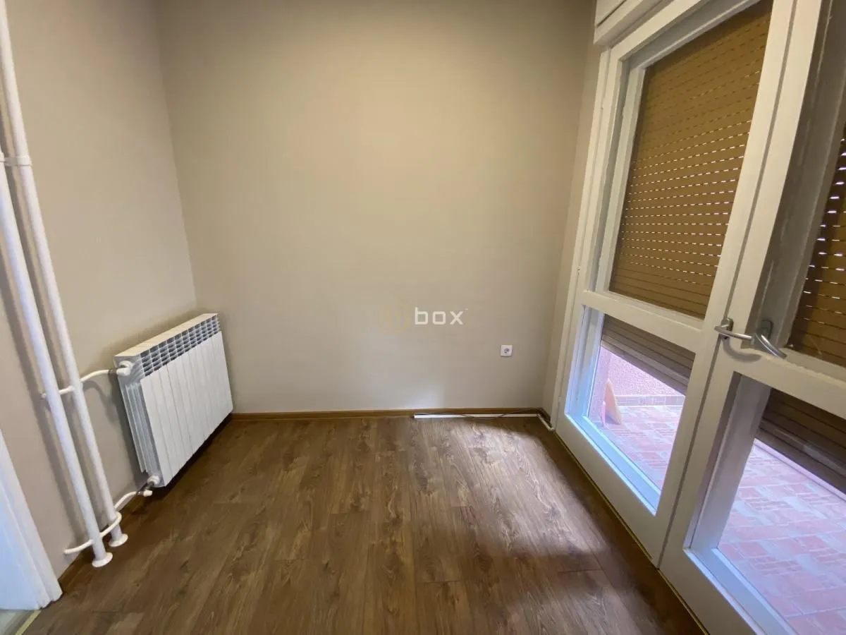 Empty room with wooden flooring, a radiator, and balcony doors.